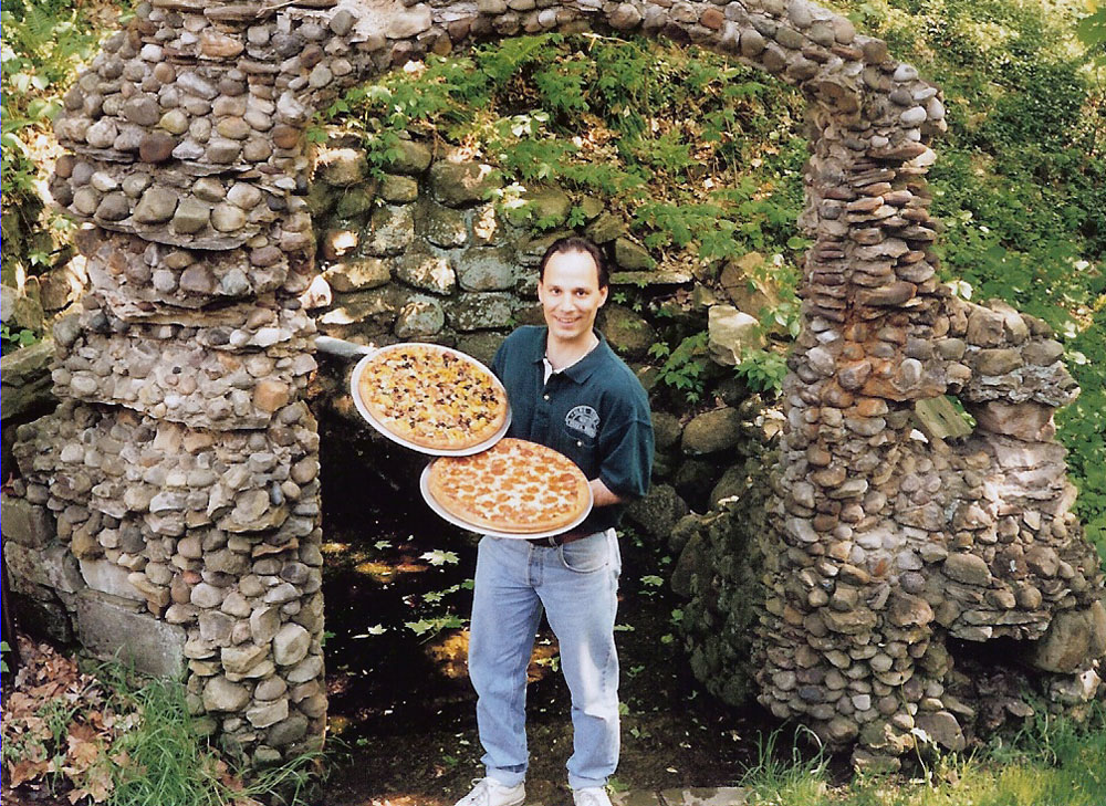 Darrell, co-owner of Olde Town Pizza House, holding two fresh pizzas